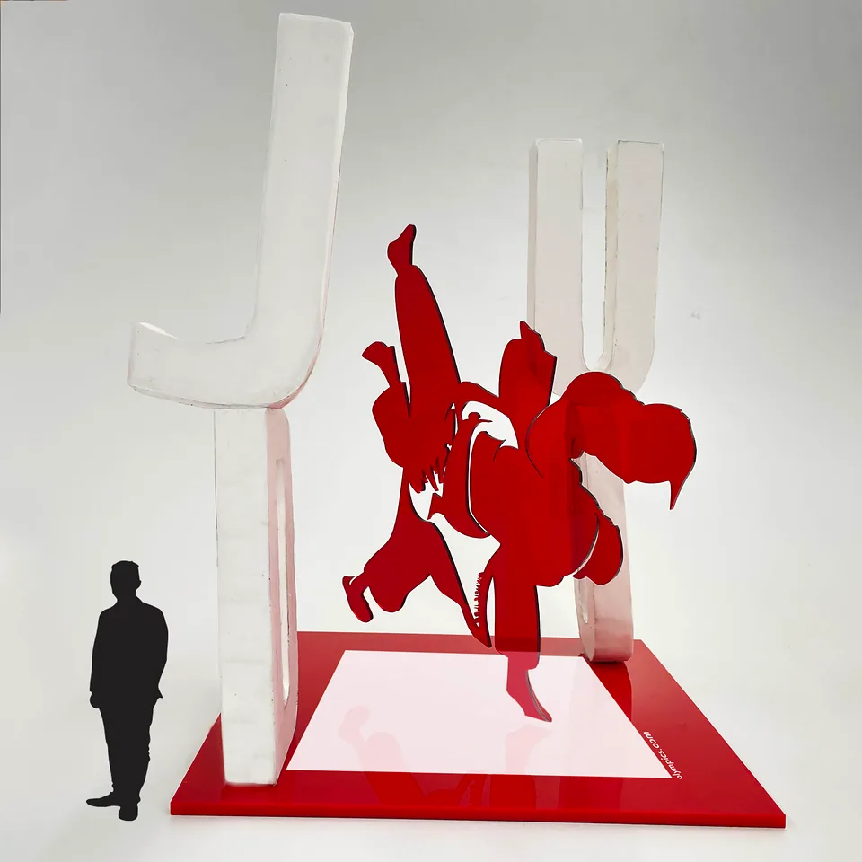 3D informative sculpture of two judo athletes in red and white, with a human figure for scale